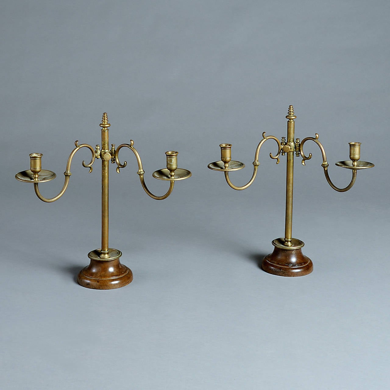 A PAIR OF LATE GEORGE III LACQUERED BRASS AND OAK CANDELABRA WITH ADJUSTABLE ARMS AND TURNED BASES, circa 1800.