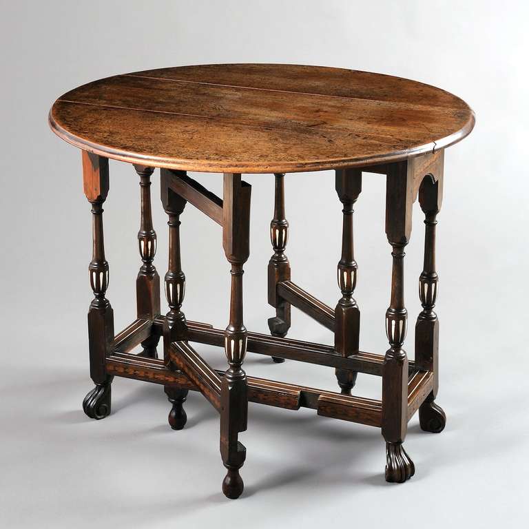 a highly unusual William III cocuswood and mahogany drop leaf table inlaid with ivory and marquetry, circa 1700.
The oval drop leaf top above an end drawer on slender baluster legs, the frieze and stretchers inlaid with strips of foliate marquetry,