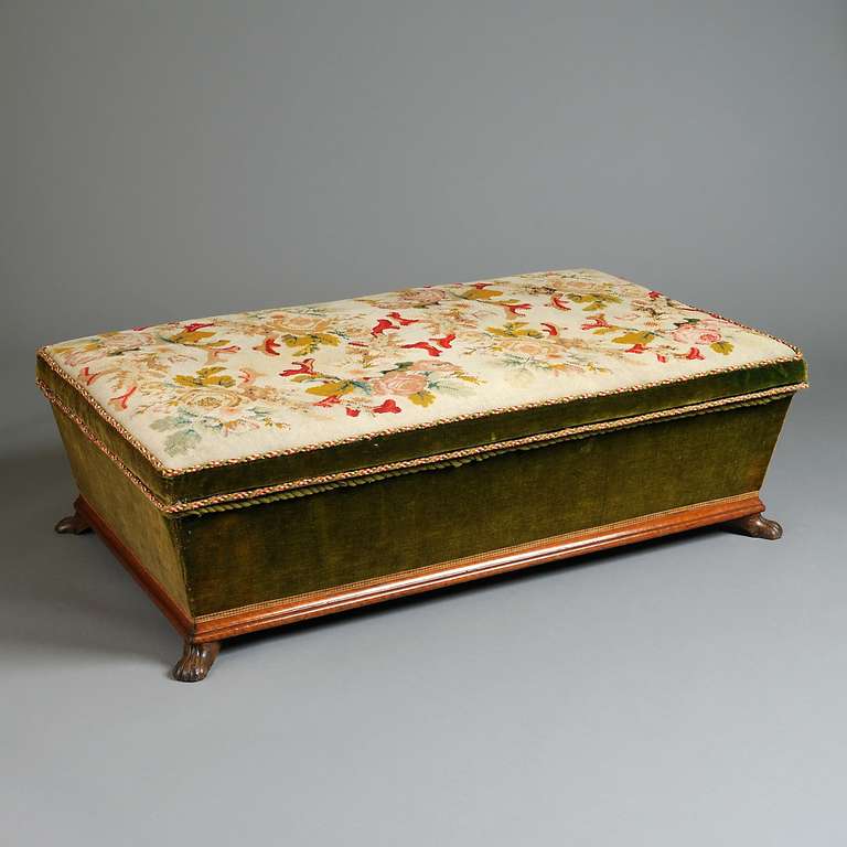 A FINE VICTORIAN NEEDLEWORK OTTOMAN, CIRCA 1850.
The hinged seat worked with coral and roses and enclosing a blue silk-lined interior, the canted sides in their original green velvet, on mahogany paw feet.