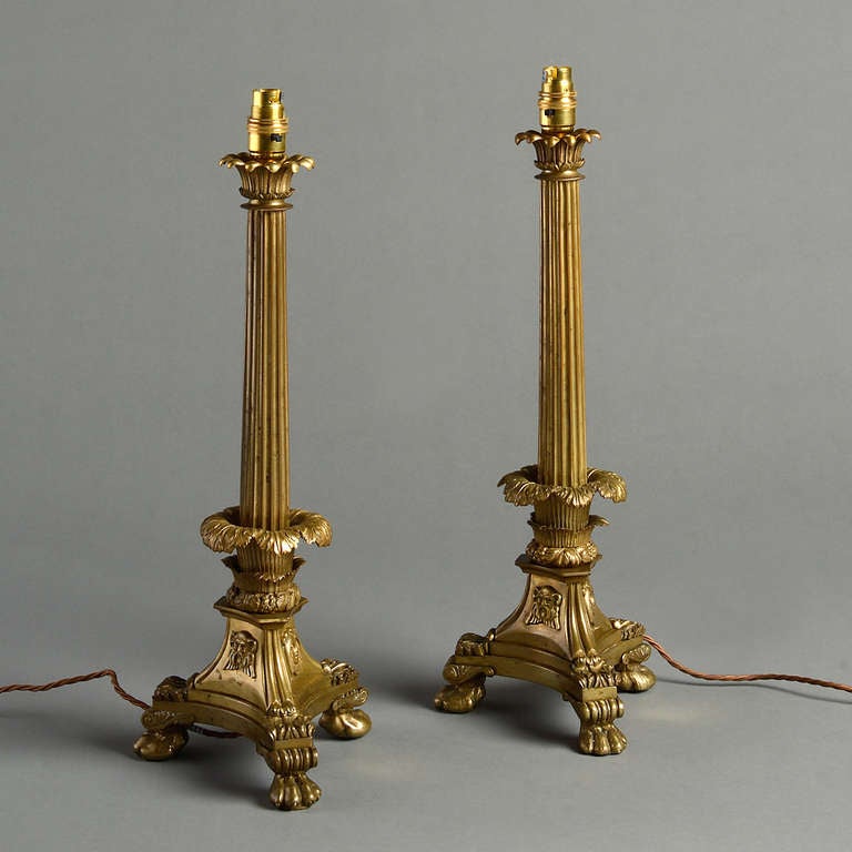 A PAIR OF WILLIAM IV LACQUERED BRASS TABLE LAMPS IN THE MANNER OF WILLIAM BULLOCK, CIRCA 1830.
Each with lotus leaf capital and reeded column on a triangular base applied with classical masks.