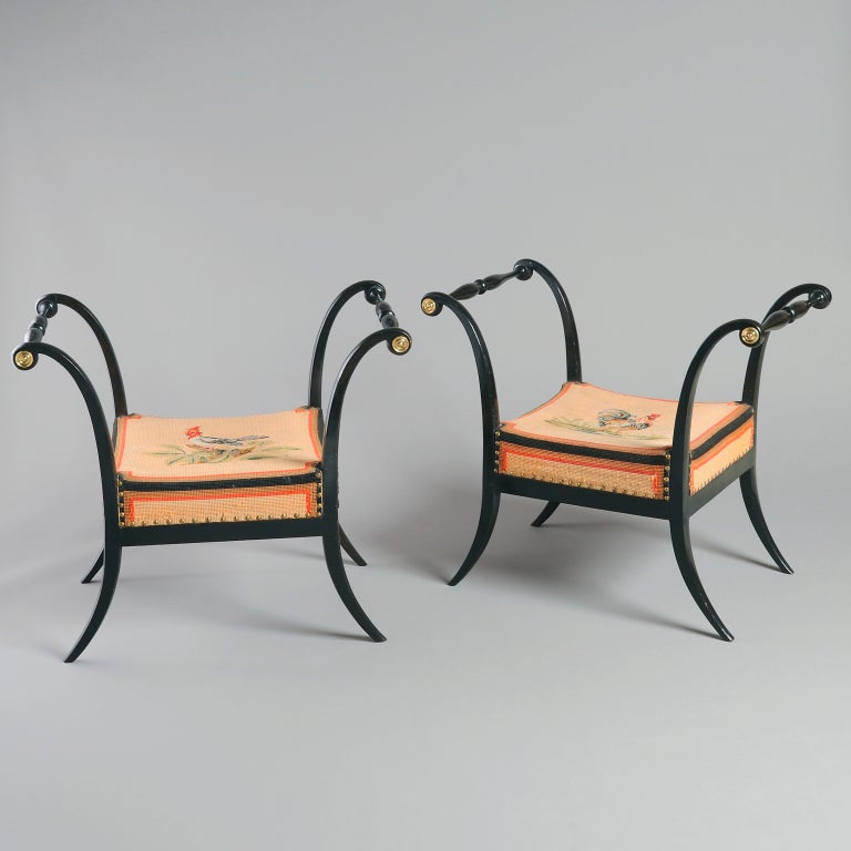 A pair of North Italian gilt-metal mounted ebonized stools with original needlework seats, probably Parma, circa 1815.
