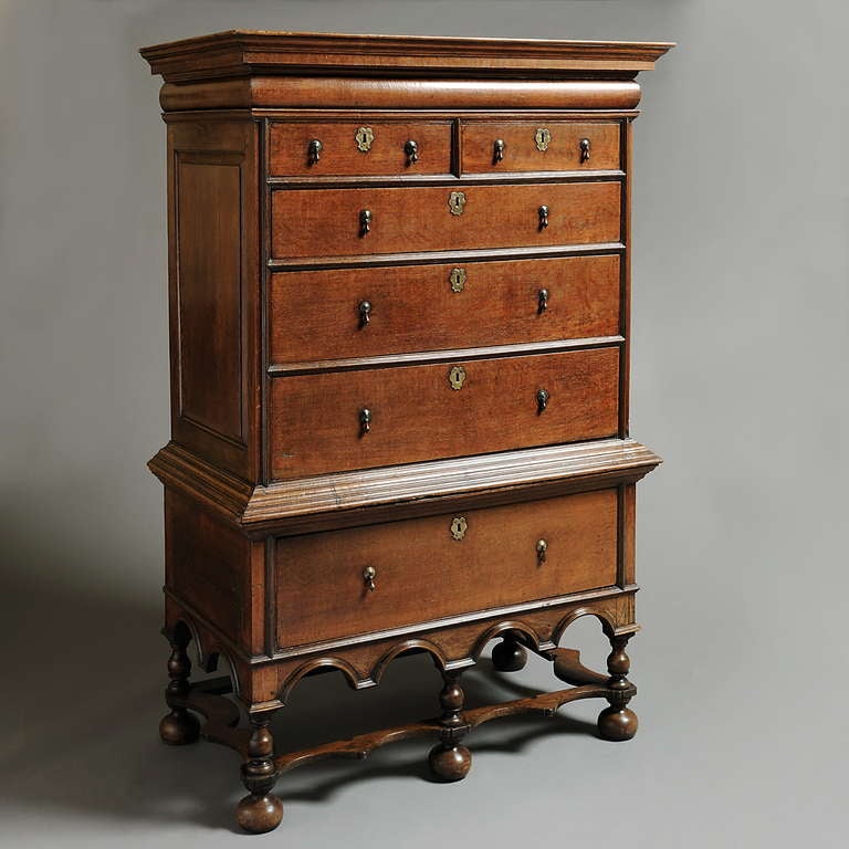 A WILLIAM & MARY OAK CHEST-ON-STAND, CIRCA 1700.
With concealed frieze drawer above two short and three long drawers, the stand with a deep drawer above an arcaded apron on turned legs and bun feet joined by shaped stretchers, with original