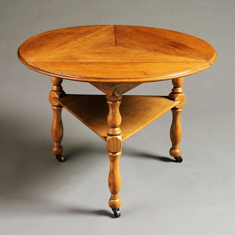 AN UNUSUAL OAK TABLE DESIGNED BY SIR EDWIN LUTYENS, CIRCA 1900.
With circular triple drop-leaf top on turned legs joined by a triangular undertier, with original brass castors.

There is an identical table at Bois des Moutiers, Normandy, the