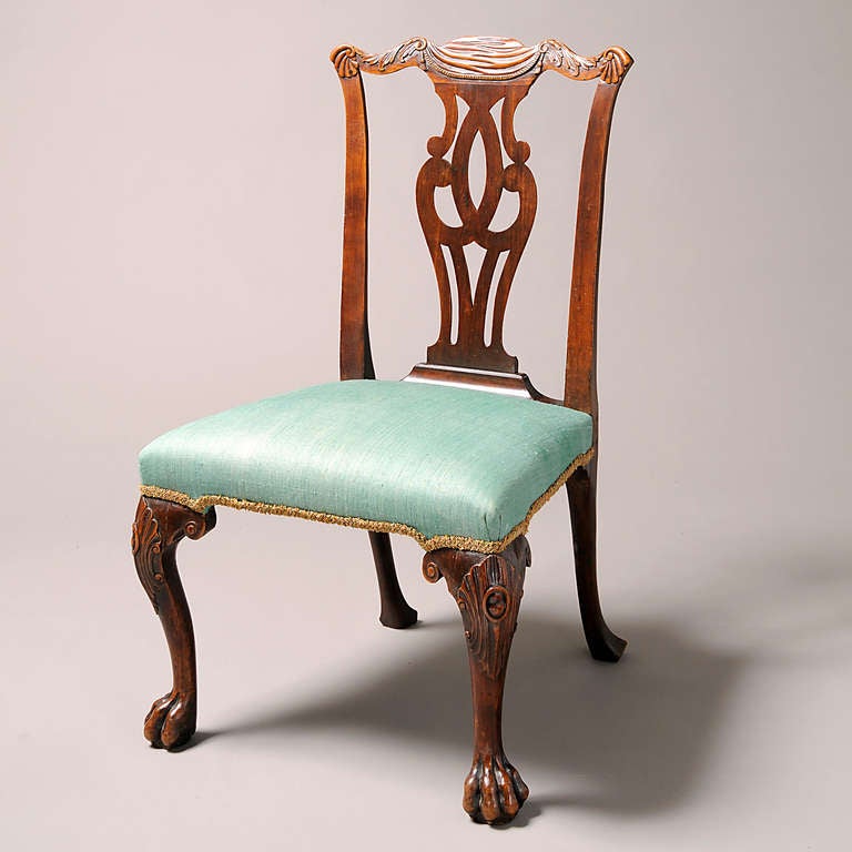 A FINE GEORGE II FRUITWOOD SIDE CHAIR, CIRCA 1750.
The shaped top rail carved with a swag and tassels, acanthus leaves and scallop shells, above a pierced splat, on cabriole legs and paw feet, the knees with foliage, scrolls and cabochons.