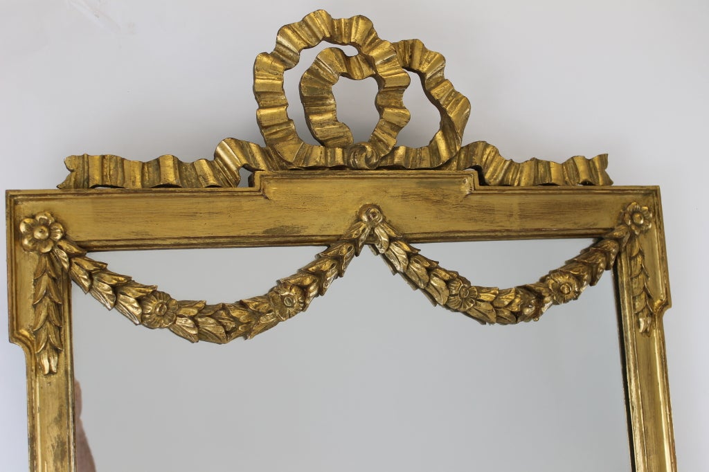 Large gilded frame mirror with ribbon and garland details. .