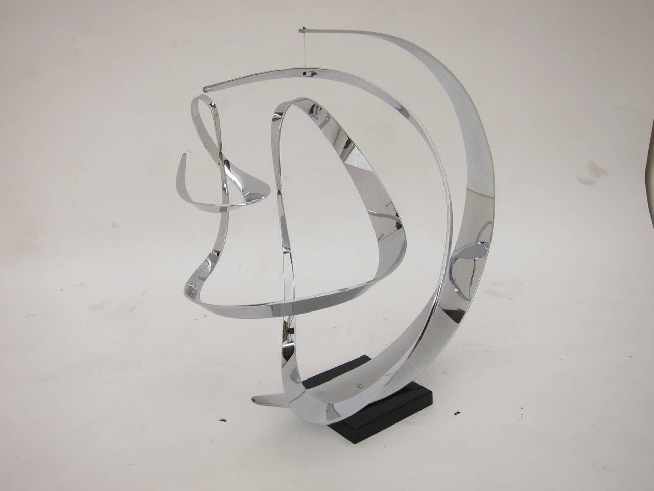Kinetic sculpture by John W. Anderson. Solid polished aluminum on acrylic base. Signed and dated 1974.