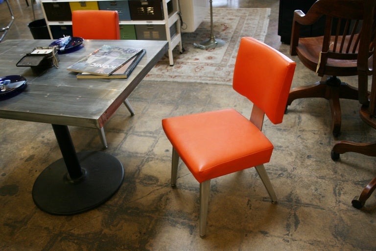 A pair of 1980's General Fireproofing Company guest chairs in aluminum and orange vinyl upholstery.