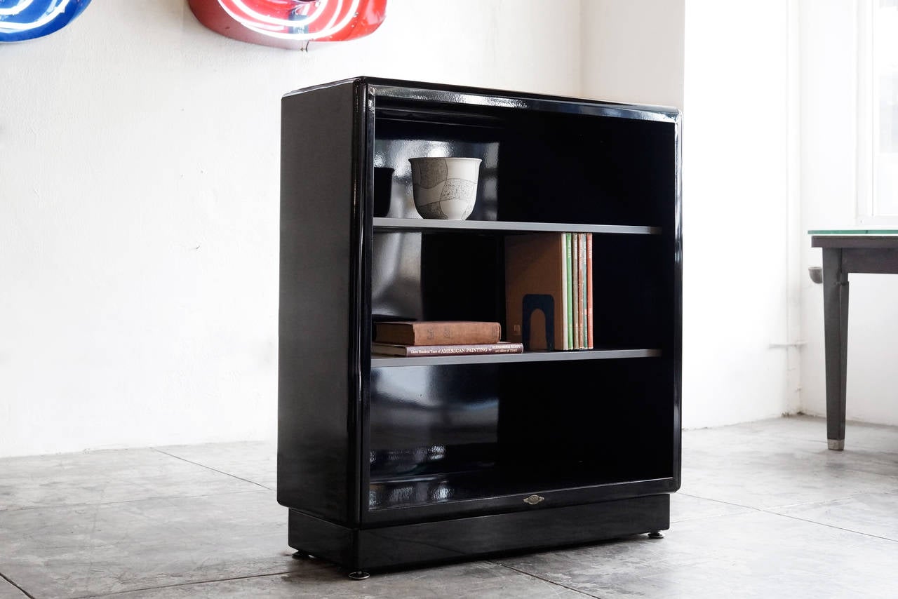 It's the Classic three-shelf all steel vintage tanker bookcase refinished in high gloss black with matte grey shelves. This minimal, Mid-Century unit with its adjustable shelves, is perfect for storage and display.

This unit is in excellent