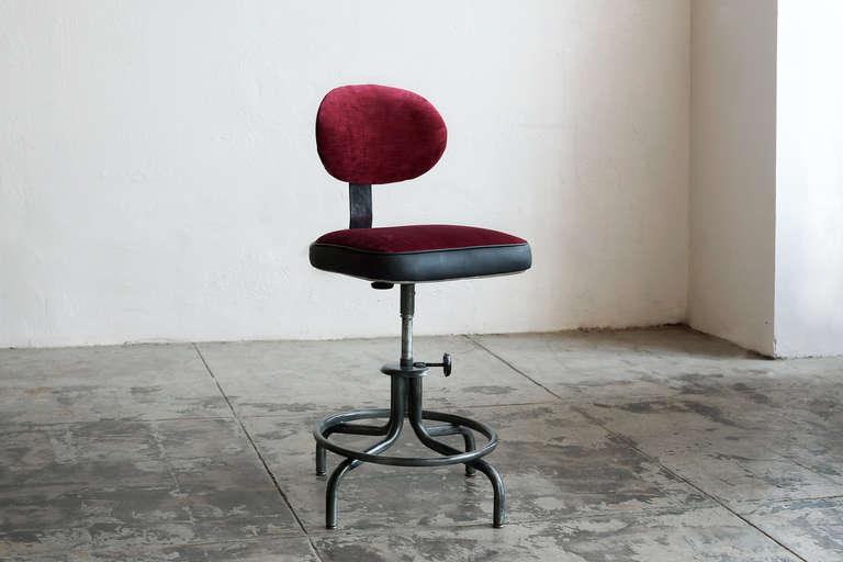 This iconic mid-century drafting stool is beautifully refinished in a black-cherry velvet and charcoal vinyl trim with piping. The steel frame has a great patina, clear-coated to prevent further wear. Swivels and adjusts.