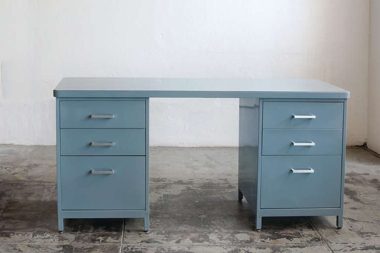 The vintage tanker knee-space credenza offers the storage capability of two file drawers and four box drawers with the added functionality of a slim desk. We restored this piece in a Smokey blue powder coat.