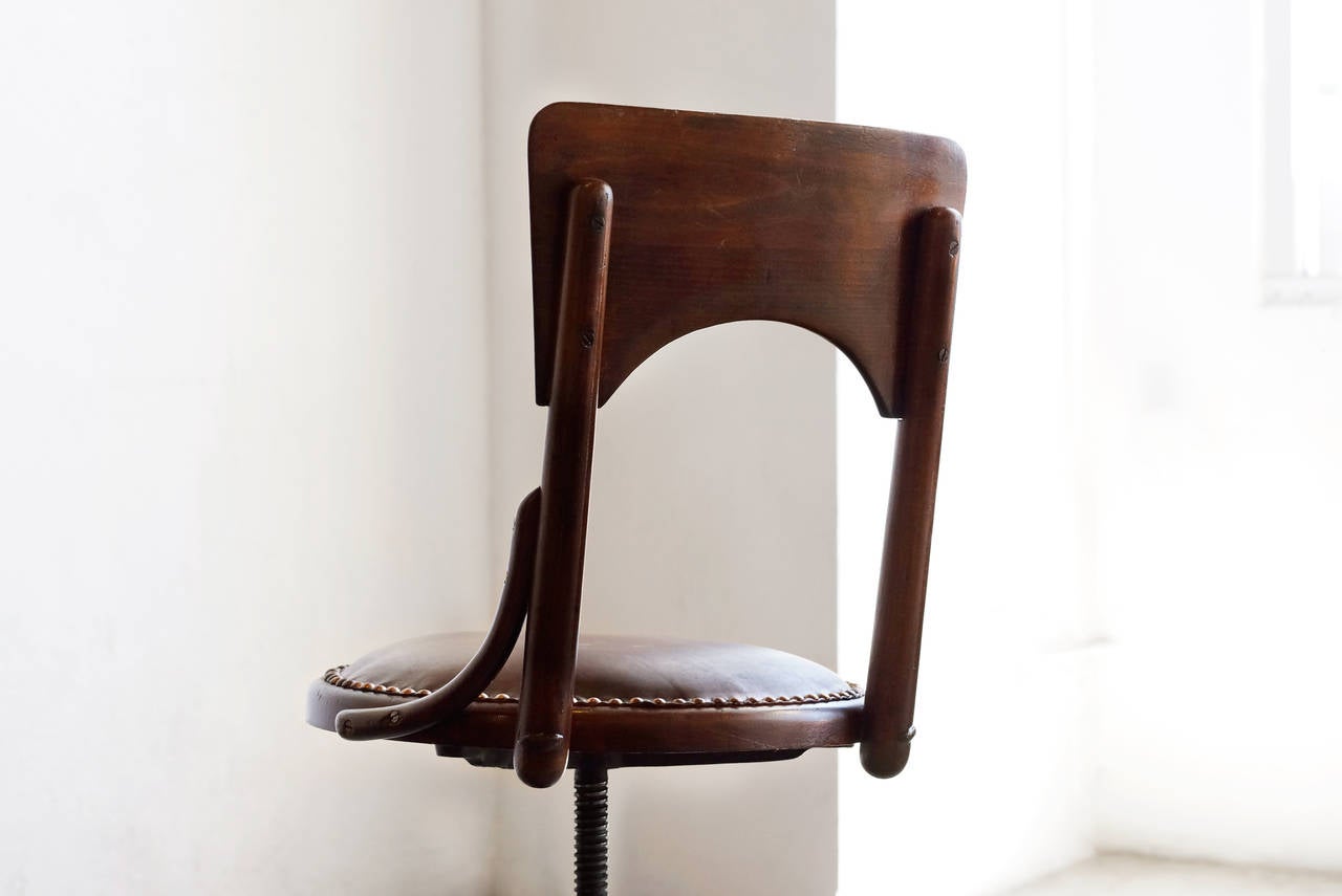 Antique oak and cast iron drafting stool with back, c. late 1800s. Newly reupholstered seat in tufted leather. Swivels. A highly unique chair with wonderful lines and details. Numbered M80. 

23