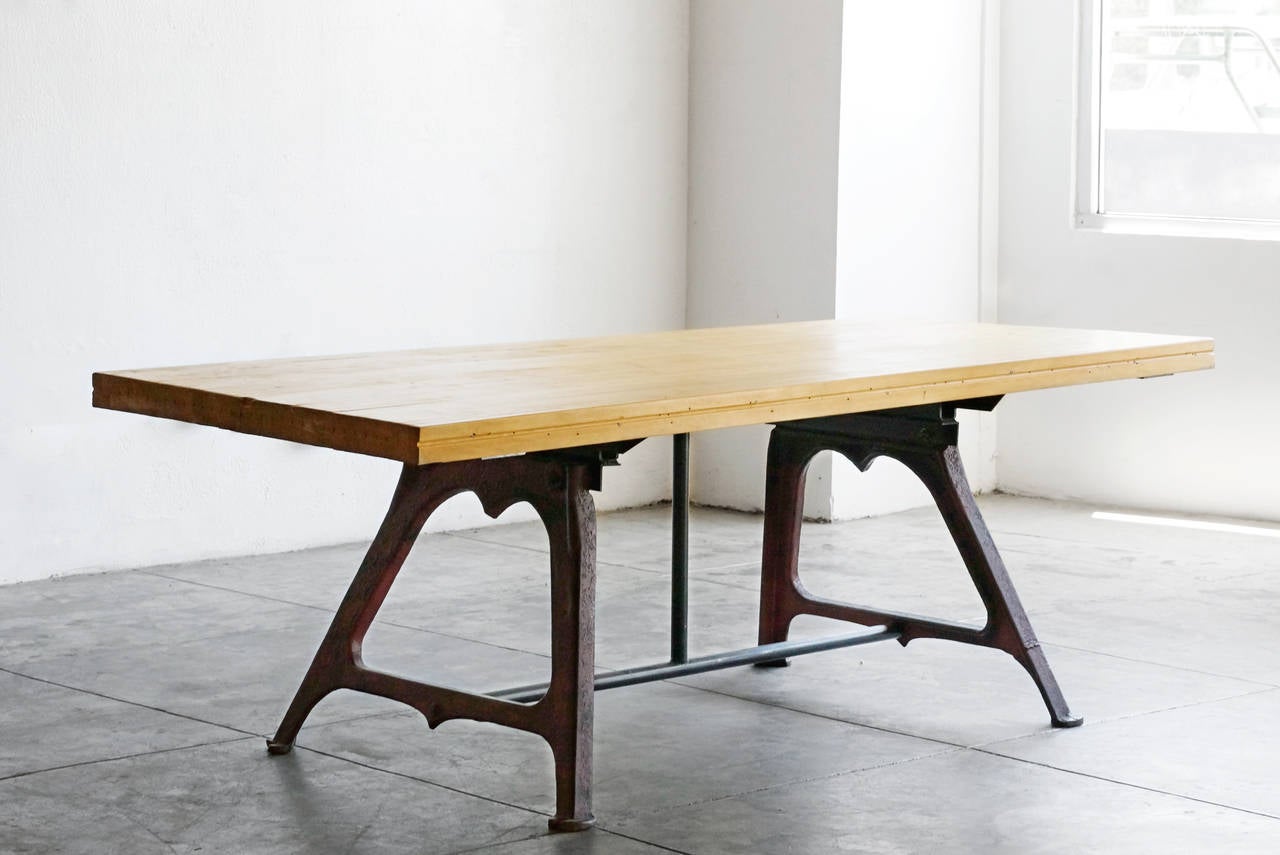 Excellent reclaimed dining/conference table composed of antique cast iron machine bases and maple bowling Lane top. Bases feature original red painted patina.

Dimensions: 36