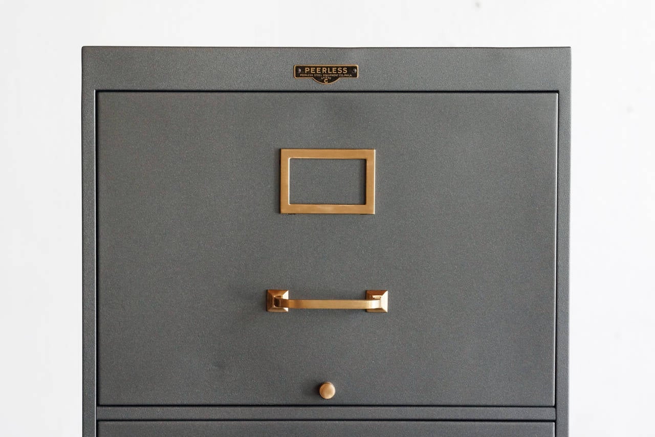 1930s steel file cabinet by Peerless Steel Equipment Co., Philadelphia. This uncommon 4-drawer vertical unit is newly refinished in specialty grey paint with a slightly sateen/metallic finish. Original brass hardware, brushed and polished.