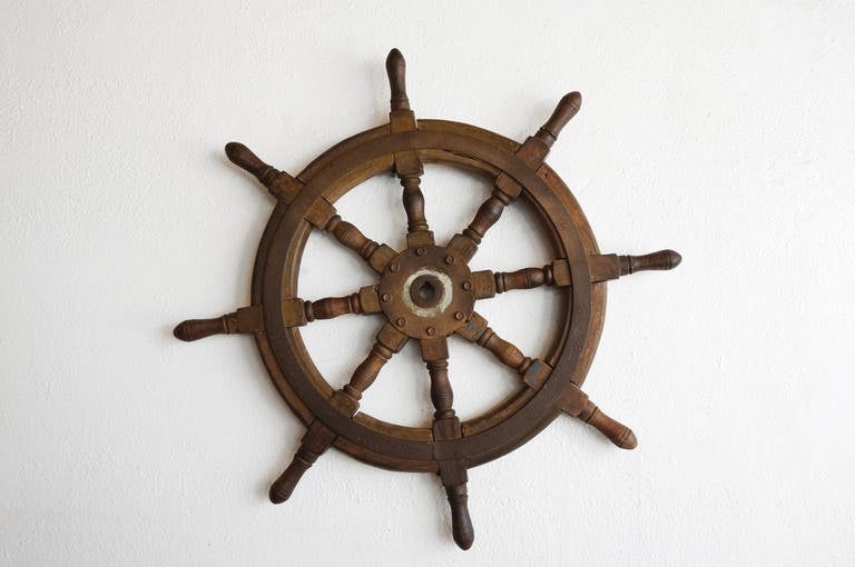 Antique ship's wheel, c. late 19th/ early 20th century. Constructed of thick natural teak wood with a steel core. In solid condition with a worn-in patina. Ready-to-hang nautical wall decor.

Dimensions: 34
