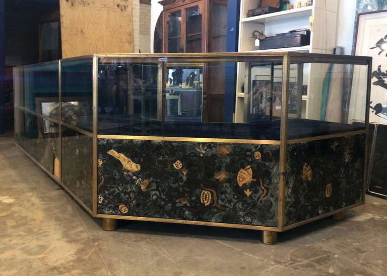 A beautiful brass and painted glass display cabinet from the I. Magnin department store in Beverly Hills, CA. 

Hand painted glass panels grace the bottom sections, with lighted display areas on top. Sliding doors on the back of cabinet, with