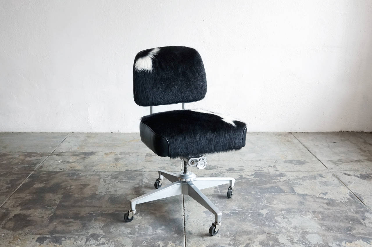 This classic 1950's steno chair has a newly refinished brushed aluminum frame paired with cowhide upholstery for a unique, updated look. Features original, iconic hardware.

Adjusts, swivels, and rolls on casters.

Dimensions: 25