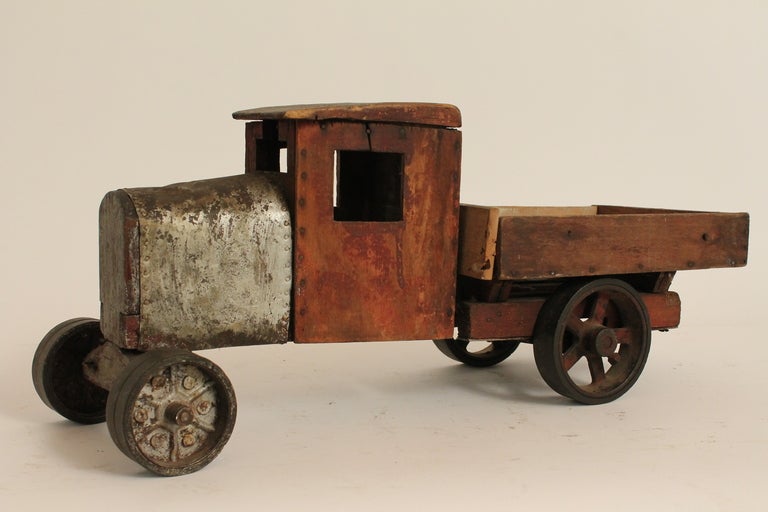 Early 20th Century Folk Art Handmade Toy Truck.
Wonderful naive construction with great surface.
Original painted pine structure with tin hood and cast iron wheels.
Potential older repair to one side of the bed , in that the wood is less worn on the