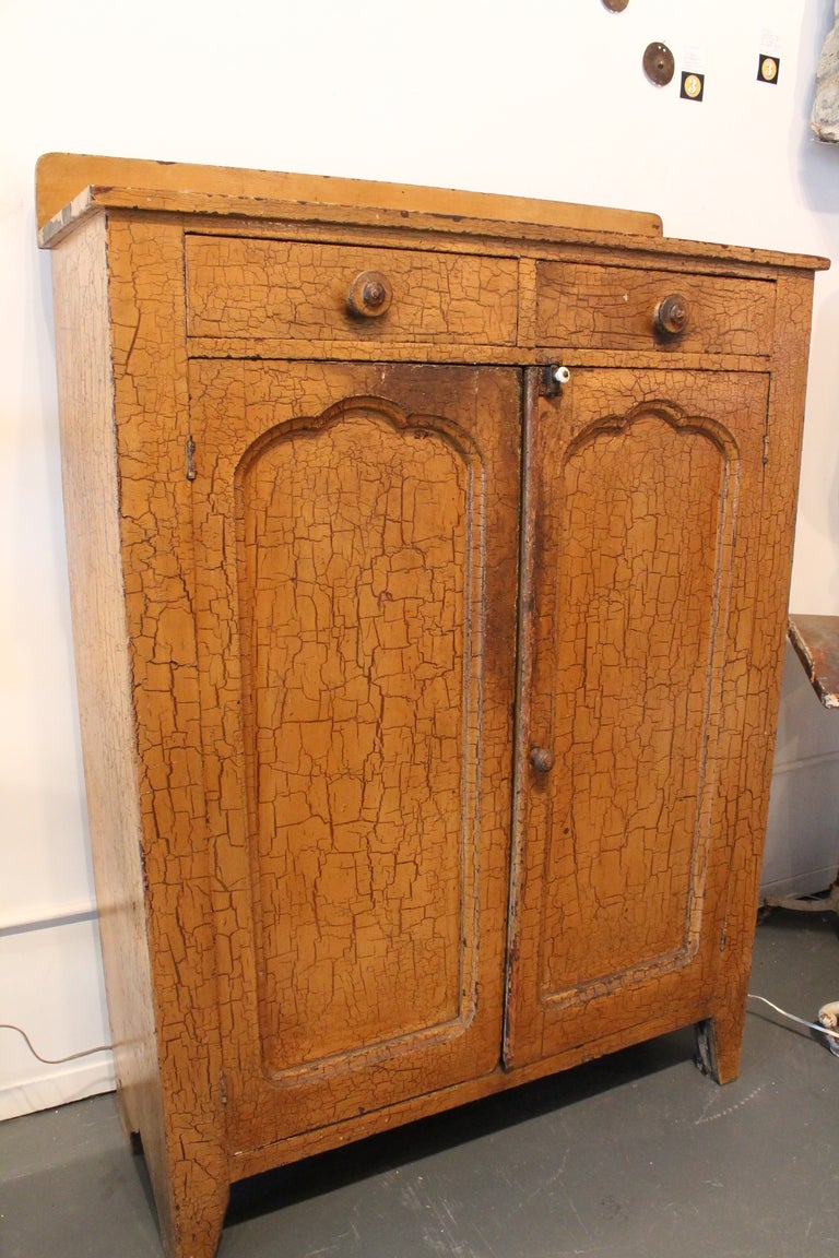 This pine cabinet has amazing original mustard paint that has crackled to perfection over the years. There are 2 drawers and the interior has 2 shelves. All original everything with fantastic surface and wear. The right hand side was never painted