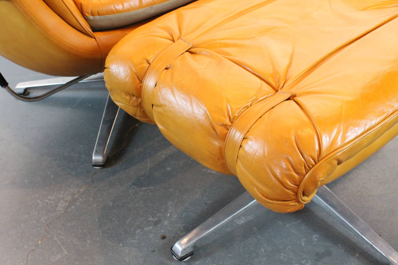 Great Mid-Century large-scale and very comfortable Overman of Sweden swiveling pedestal lounge chair with matching ottoman. Pumpkin leather-like strapped, buckled and tufted cushions over a vinyl clad egg shaped chair. Leather-like strap-tufted