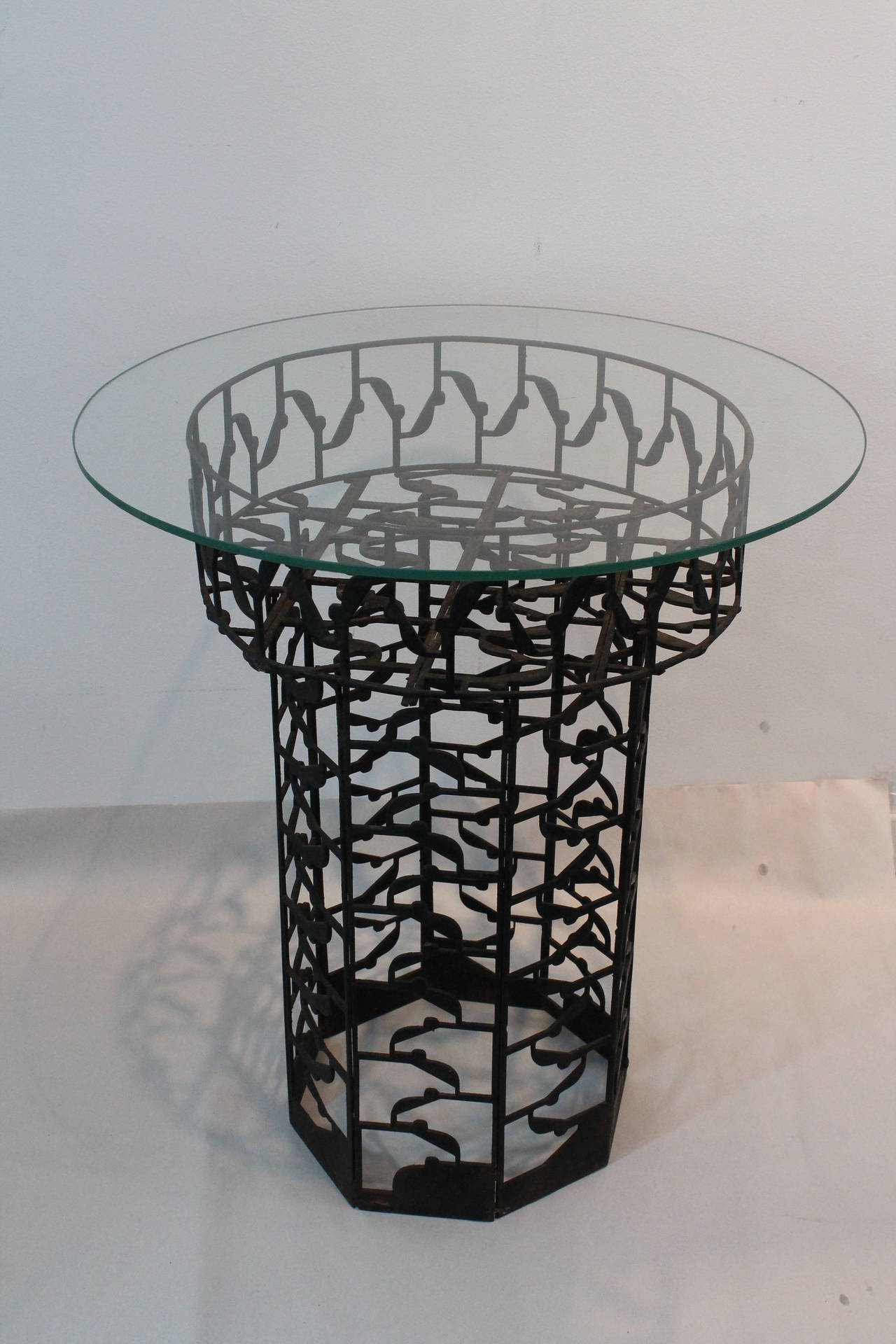 Curious stamped iron side table or plant stand that is constructed from salvaged machinist plate steel cast offs. The individual strips were ingeniously welded together to create this form.
The glass top can be removed and the table becomes a plant