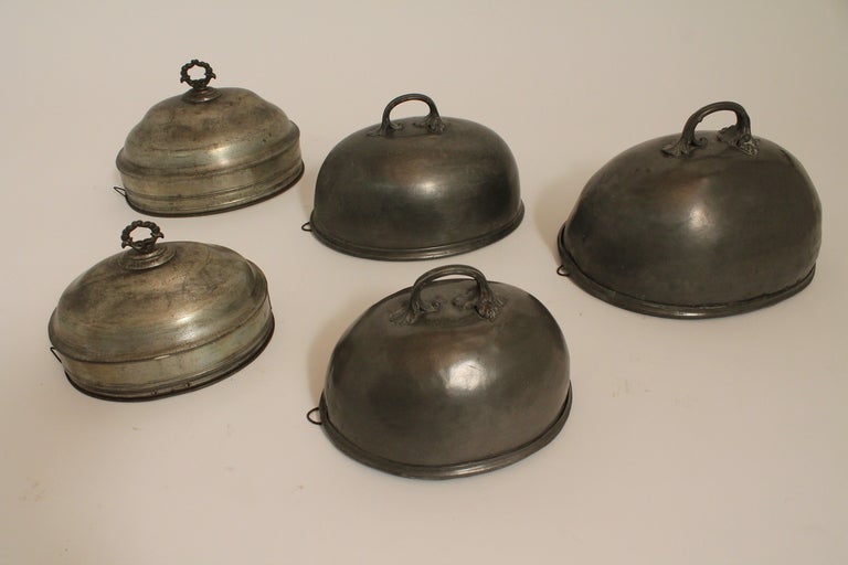 Three of the oval dish covers are a matching pewter set with the mark of Shaw and Fisher , Sheffield , as shown in image 5. The other 2 are composed of a different metal and have different handles , and are not marked.
They each have a hanging hook