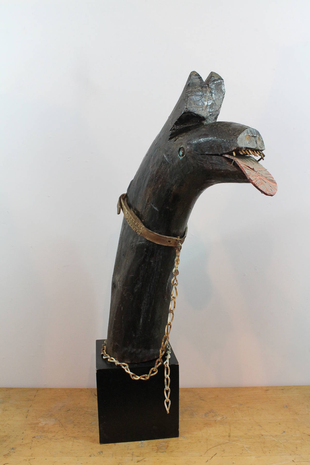 Great scale and presence on this Folk Art protective dog sculpture with a leash and chain.
Great surface on the Primitive form log head with nail teeth and a leather tongue.
Mounted on a base.