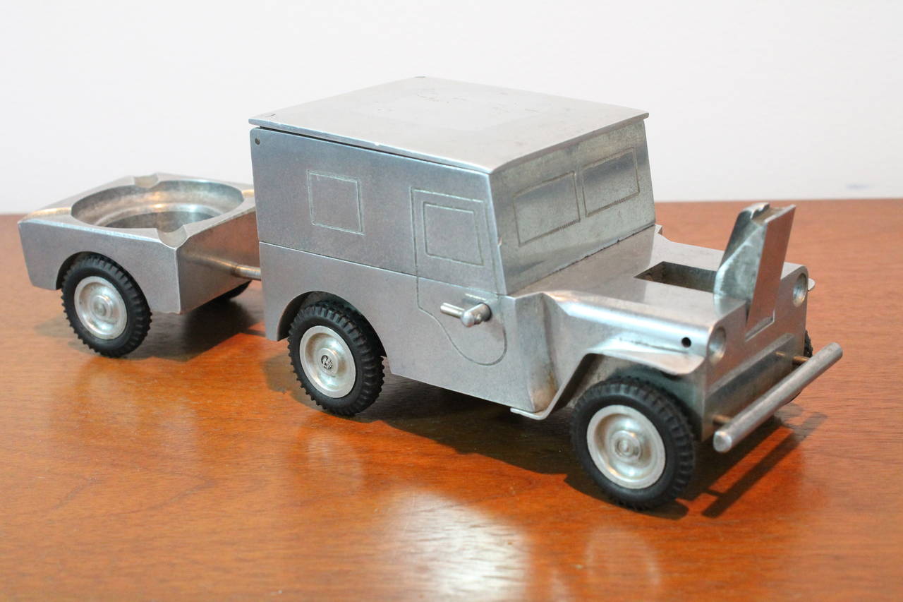 1940's table top cigarette case, lighter and ashtray combo in the form of a WWII era Ford Willy MD Jeep. The body is made from a casted block of aluminum which has been hand machined and etched with detailing all sitting on real rubber wheels. The