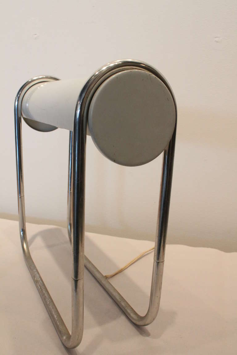 Fantastic minimalist design on this Art Deco table lamp designed by Walter Von Nessen ( 1889-1943 ) for Nessen Studios.
Chrome tubular steel loop that is the base and holds the cylindrical white enameled steel shade.
Nessen tag inside the shade.