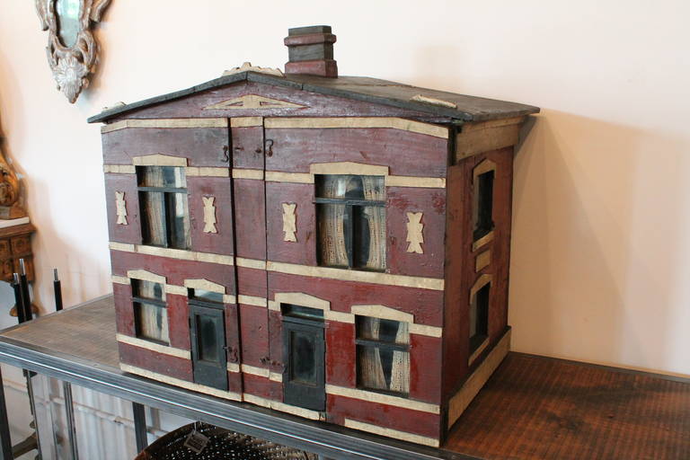 Fantastic architecture on this Folk Art American doll house from the late 19th- early 20th Century.
The facade opens on both sides with a separate door for each side. Great original paint and graphic simple architectural details.
The inside has