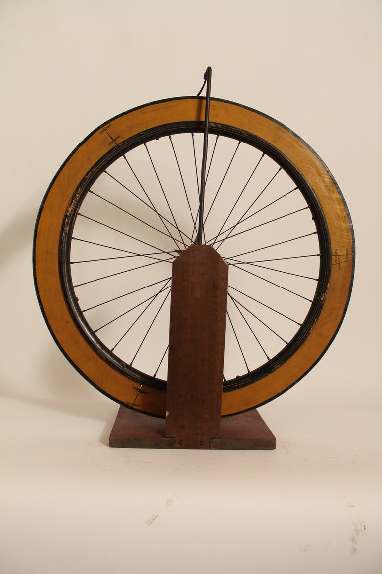 This graphic Carnival Wheel is constructed of a wood rimmed bicycle wheel with hand painted numbers around the perimeter. It is freestanding on a painted base and has a wonderful star design detail at the hub of the wheel. Great surface and color.