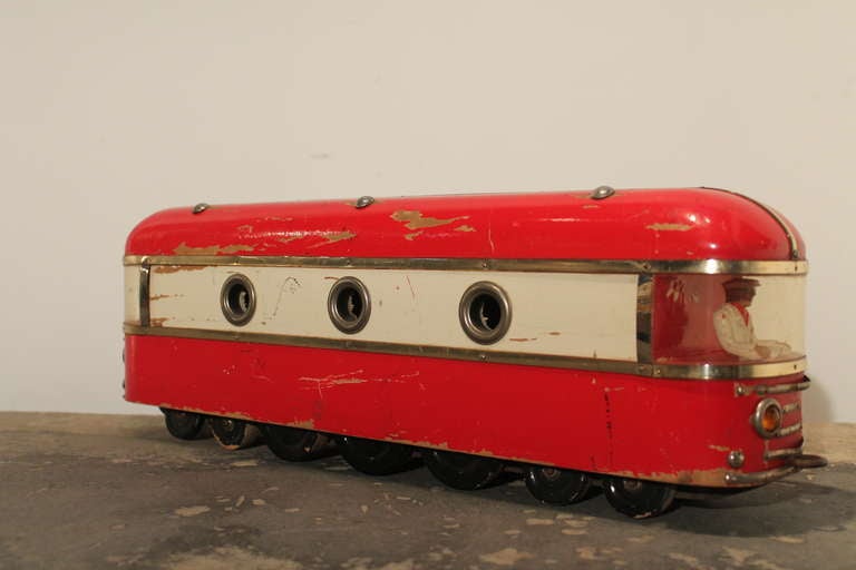Wonderful form and color on this large Deco wood toy train.
There is a rather snappy dressed gentleman at the front of the car. Great circular windows.
One of the headlights is missing , as can be seen in image 3.