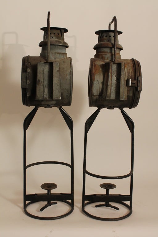 Pair of graphic and sculptural Railroad lanterns on tall iron bases.