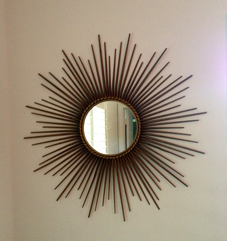 A vintage sunburst wall mirror from France made by Chaty Vallauris. Gilt metal frame with braided accent around the mirror. The mirror is of a diameter of 10 inches. This is one of the pair same sunburst mirrors except the other has a convex mirror.