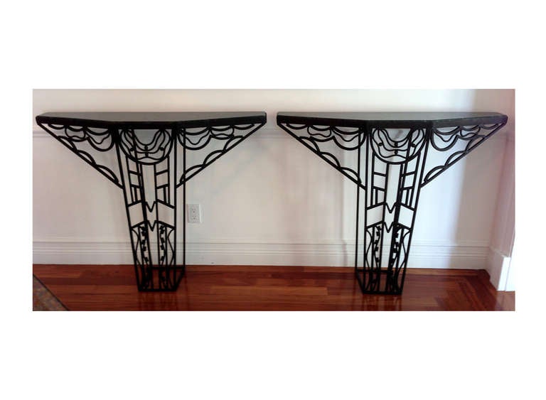 A pair of Art Deco console table in wrought iron frame, likely American circa 1930s. Open frame ironwork is designed with one pedestal. The classic Art Deco geometrical motifs with fine details entail an abstract bird with spread-out wings. Each