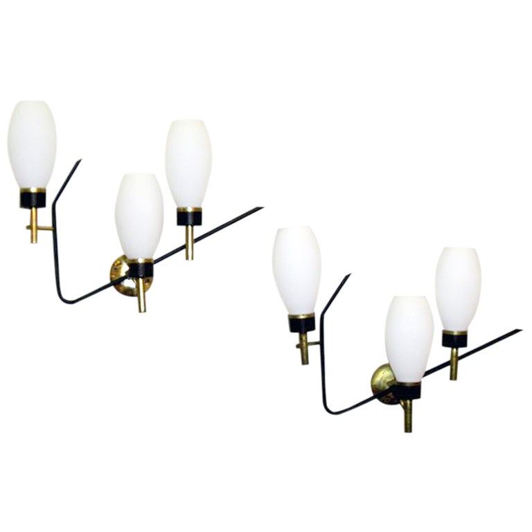 A pair (three actually available) beautiful Italian wall lights / sconces by Stilnovo. Great sense of proportion with contrasting black enamel tubes and polished brass branching into three tulip buds of blown blown-glass shades. Elegant, understated