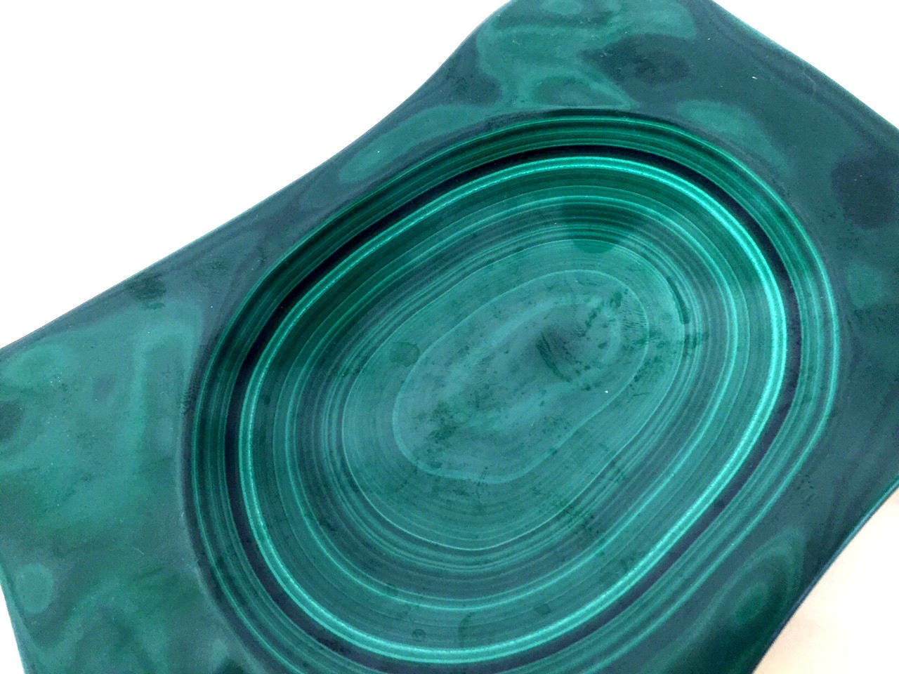 A decorative dish or bowl fashioned out of a large piece of all natural malachite mineral stone. Polished beautifully to display the natural swirly layering and concentric of the stone. It can be used as a center piece or a decorative vessel.