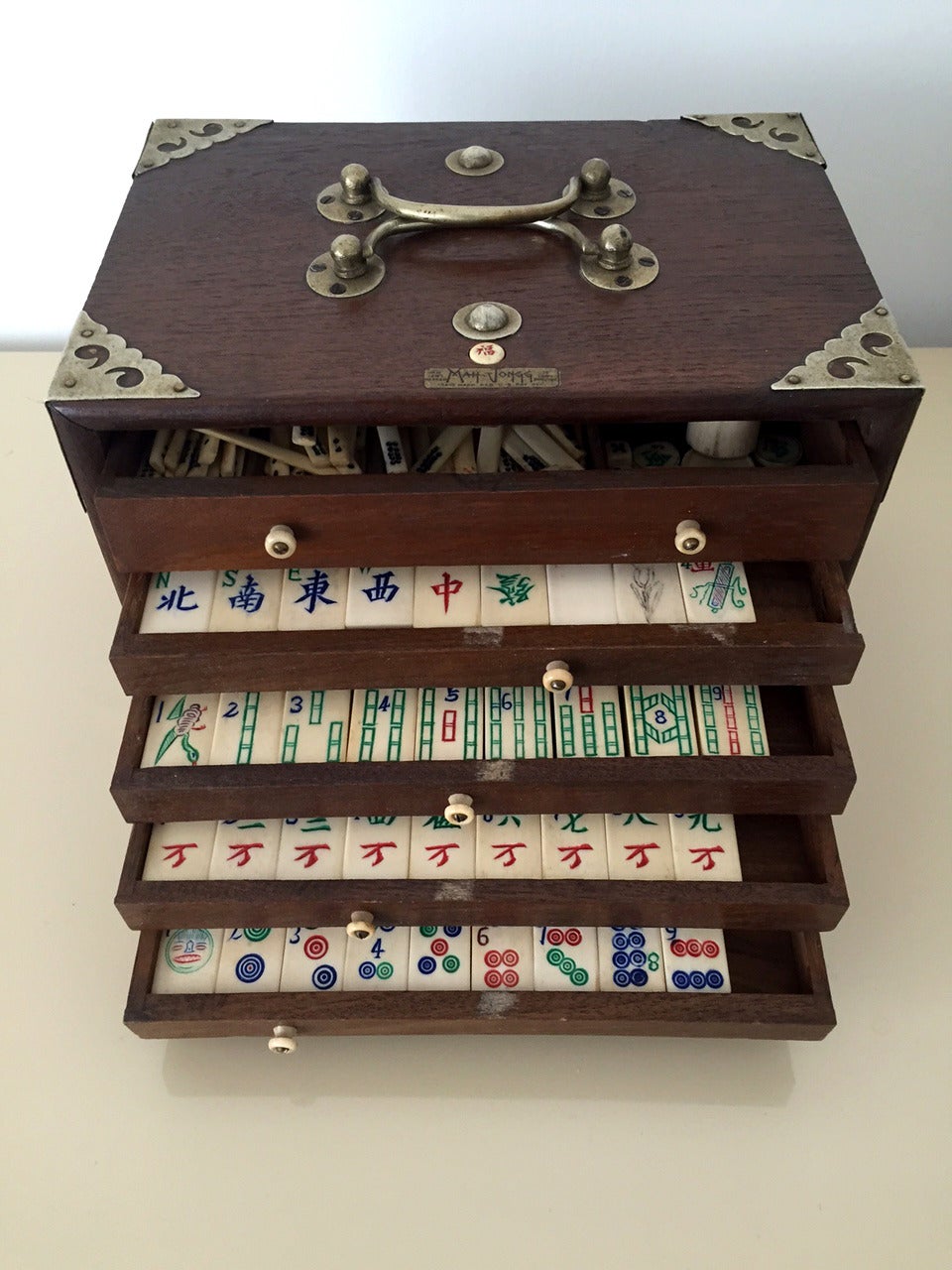 A complete set of Mahjong game  with tiles and sticks made from bone and bamboo. They are housed in the original boxes with multiple drawers befitted with bone pulls, brass handles and hardware. The spring door is designed to be open with a push of