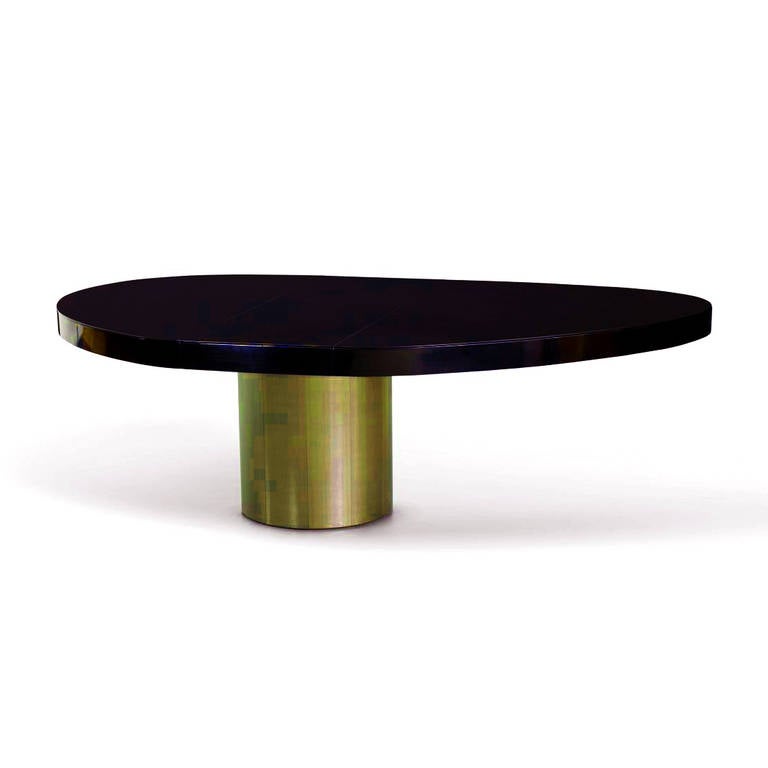 A dining table by Paul Evans circa 1981. Free pebble form top in black lacquered finish supported by a brass plated pedestal base. Sculptural in form with a slight asymmetrical appearance. A central leaf will extend the table from 75.5 to 95.5