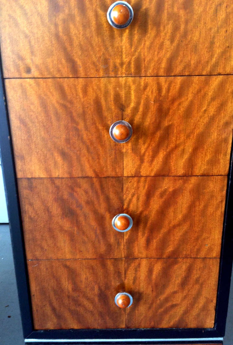 A pair of nightstands or cabinets of drawers circa 1930-40s. It is in book-matched flaming mahogany with ebonized and silvered trims. With chrome and bakelite handles. Each has four drawers and on castors. These are great period example of American