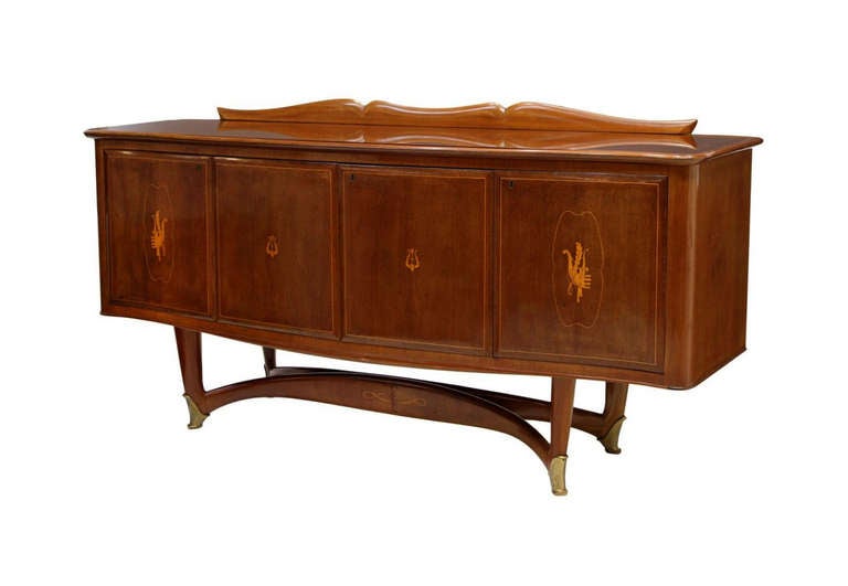 An Italian mid-century modern mahogany sideboard with lighted central bar shelf circa 1950s, attributed to Vittorio Dassi (1893-1973) circa 1950s. It features a glass top with shaped splash back over four serpentine doors, the center two doors