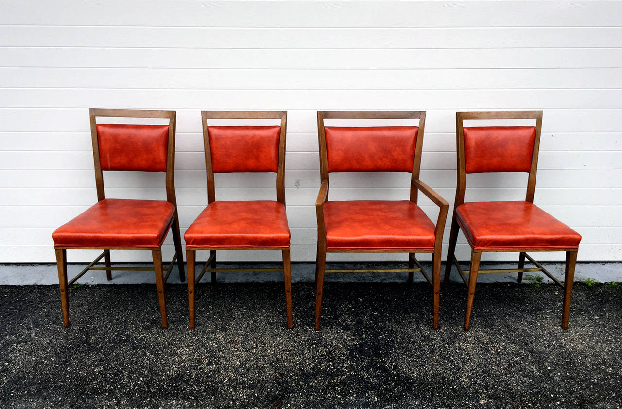 A set of four dining chairs designed by Paul McCobb as part of the Directional line. Solid bleached mahogany frame with brass stretch bars and upholstered in a burnt orange stimulated leather. Five side chairs and one master arm chair. 
These may