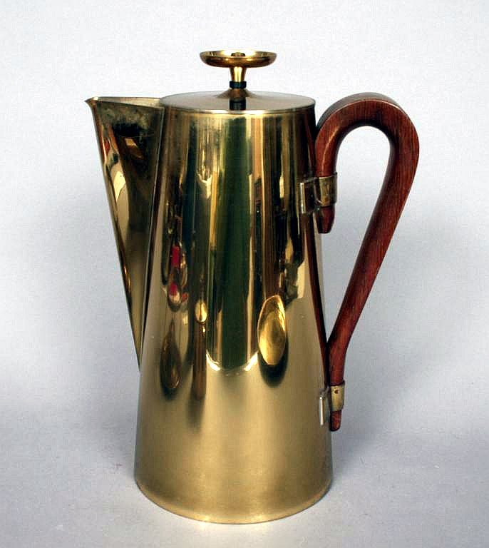 A coffee or tea serving set designed by Tommi Parzinger for Dorlyn Silversmith. The set is made of heavy brass. It consists of a pitcher with wood handle equipped with a heater, a creamer, a lidded sugar and a round tray.