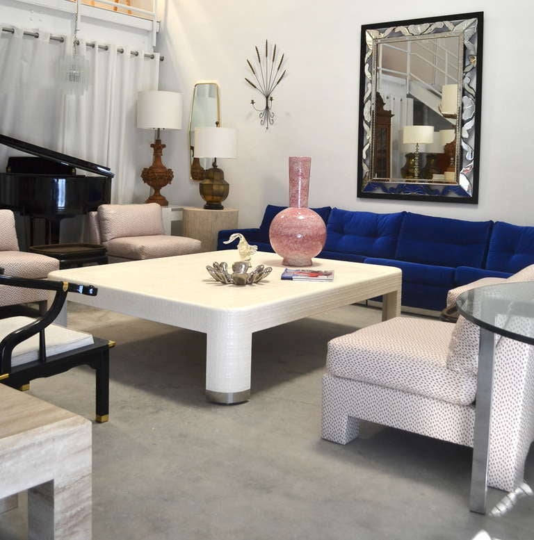 Glamorous Mid Century Modern lacquered raffia cocktail table in the style of Karl Springer, c. 1970s - 1980s. This stunning white lacquered coffee table is accented with chrome sabots.