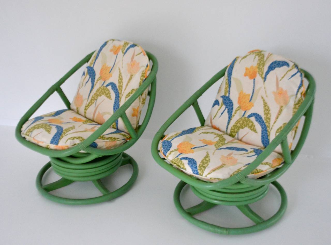 Striking pair of lacquered bamboo club chairs, c. 1960s. These lounge chairs are designed with swivel bases and cushions upholstered in an abstract floral motif cotton muslin fabric.