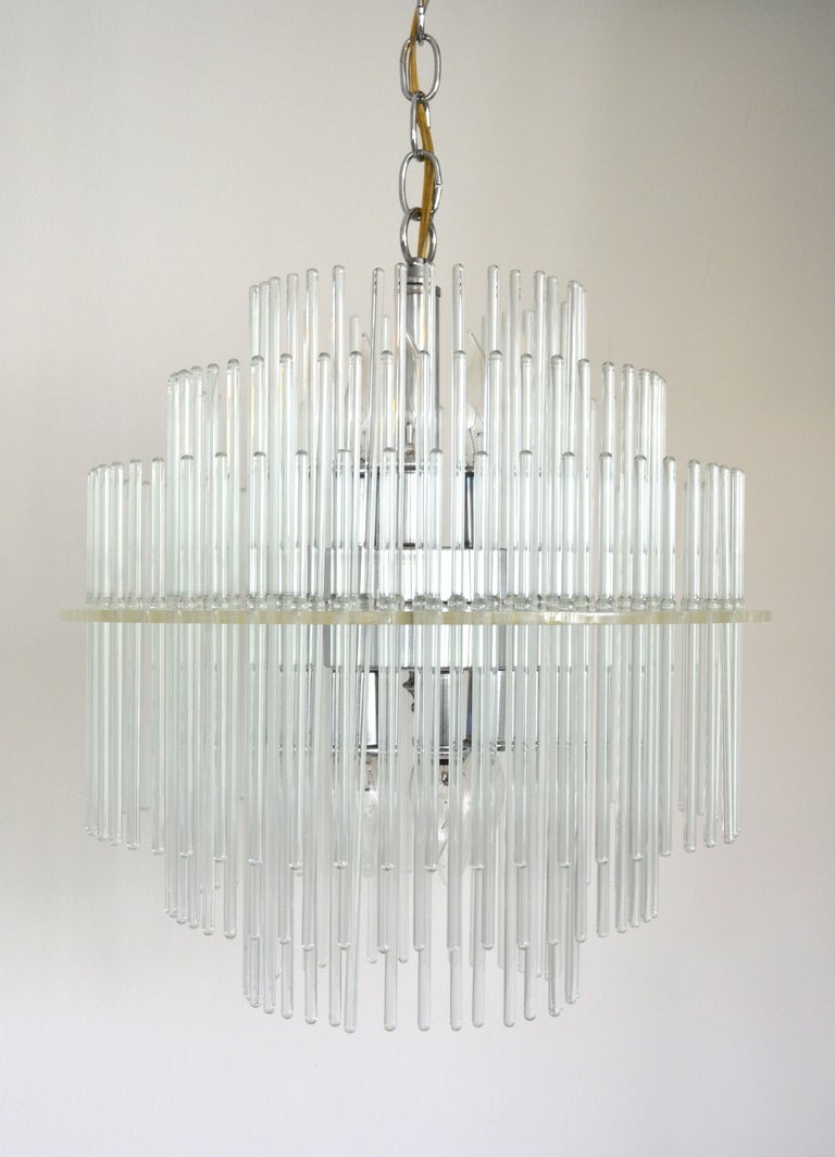 Elegant Mid-Century Modern glass and chrome round chandelier by Lightolier, c. 1960s - 1970s. This architectural and glamorous chandelier is composed of 138 glass rods of graduating length in three tiers creating a stunning cascading effect. Wired