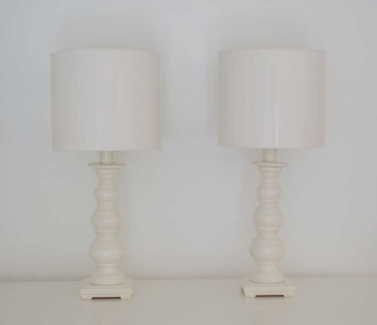 Glamorous pair of Mid Century Modern white glazed ceramic candlestick table lamps, c. 1950s - 1960s. These decorative lamps are sculptural in form and mounted on footed ceramic bases. Shades not included.