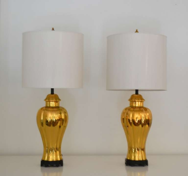 Striking pair of Hollywood Regency style gilt glazed fluted urn form table lamps, circa 1970s. These stunning and highly decorative gold glazed ceramic lamps are mounted on black lacquered bases.
Measurements:
Form: 16