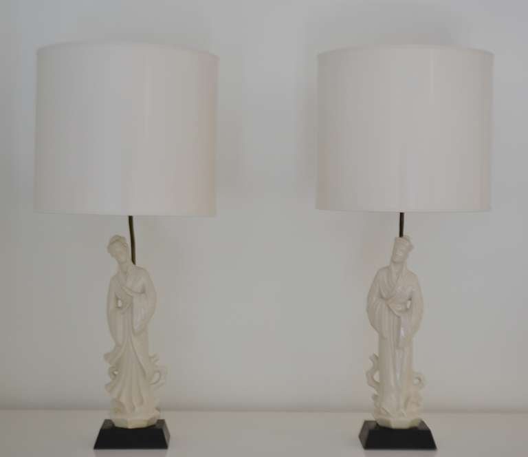 Exquisite pair of Hollywood Regency Blanc de Chine Asian figural form table lamps, c. 1940s - 1950s. These stunning lamps are mounted on black lacquered bases. 
Measurements:
Form: 17