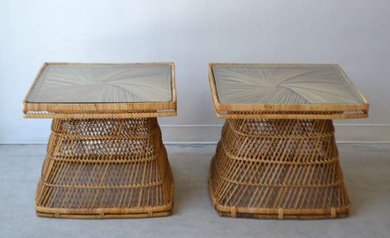 Stunning pair of natural rattan side tables, circa 1960s -1970s. These incredible Mid-Century Modern end tables or night stands are designed with intricately webbed rattan and outfitted with glass tops.