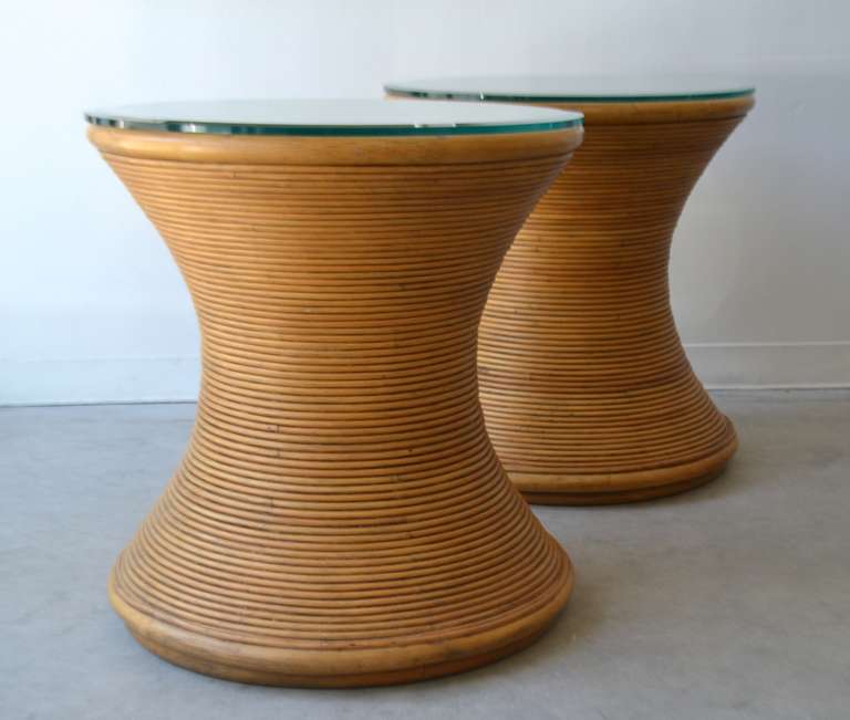 Stunning pair of sculptural cut reed side tables, circa 1970s. These custom made Asian inspired hourglass form occasional tables or night stands are designed with bands of cut reed and accented with glass tops.